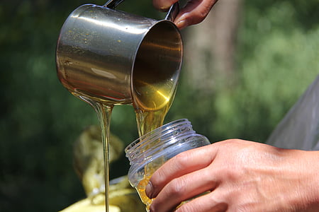 person pouring honey on clear container thumbnail