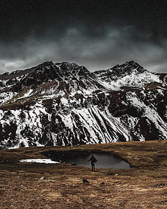 person standing near pond and mountain thumbnail