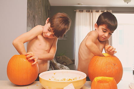 two boys putting their hands inside pumpkins thumbnail