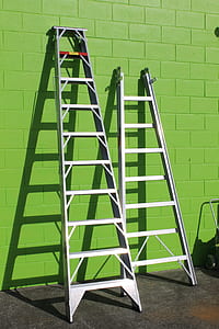 two gray metal ladders on green wall thumbnail