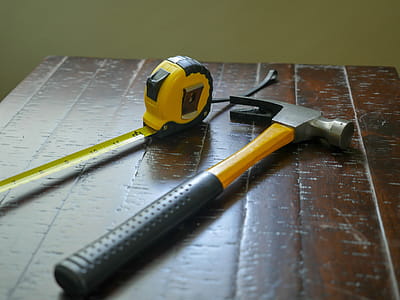 Hammer and measuring tape sitting on a wooden table thumbnail