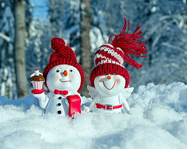 two white-and-red snowman figurines standing on snow field thumbnail