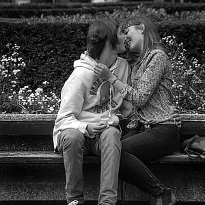 man kissing woman while sitting on bench thumbnail