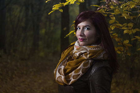 woman in brown and white scarf standing beside tree thumbnail