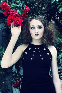 woman wearing black sleeveless dress holding red petal flower thumbnail