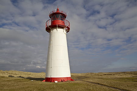white and red lighthouse under cloudy blue sky thumbnail