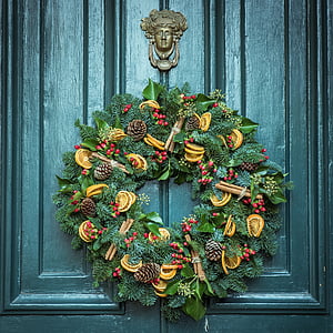 green, yellow, and red floral wreath hanging on grey wooden door thumbnail