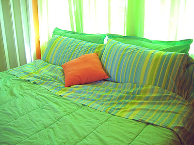 orange throw pillow on top of bed thumbnail