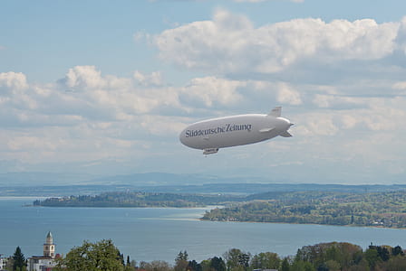 white and black zeppelin flying above island thumbnail