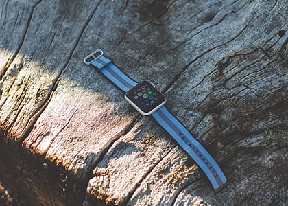 turned-on silver aluminum case Apple Watch on brown wood surface at daytime thumbnail