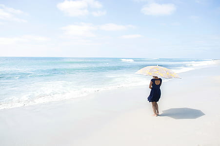 woman wearing black short dress holding umbrella on the seashore thumbnail