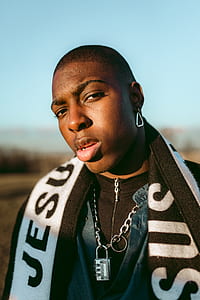 man wearing silver-colored padlock necklace standing under blue skies thumbnail