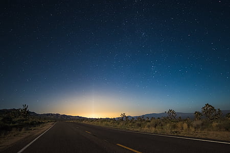 time laps photo of star night sky to sunrise on asphalt road thumbnail