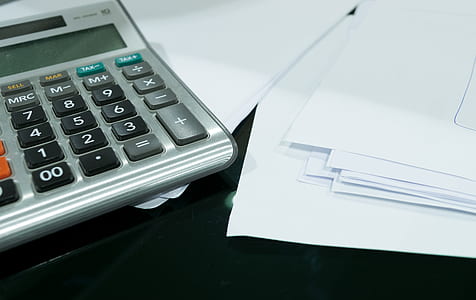 gray desktop calculator on top of stack of papers thumbnail