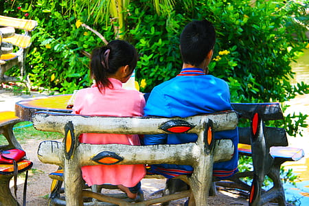 man and woman sitting on bench in front of white leafed plant during daytime thumbnail