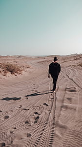woman walking on desert during daytime thumbnail