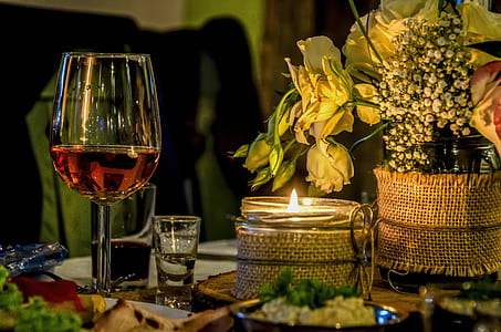 clear wing glass with wine besides lighted votive candle thumbnail