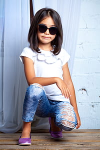 girl crouching near white curtain wearing sunglasses posing for a photo thumbnail