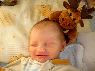 baby lying on bed beside deer plush toy thumbnail