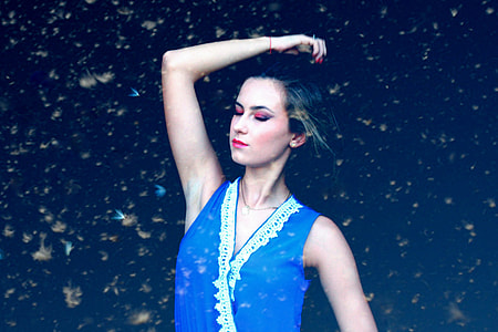low light photography of woman in blue sleeveless top thumbnail