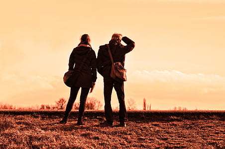 two person standing on brown open field during golden hour thumbnail