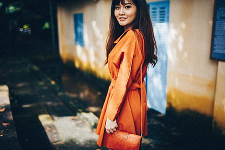 woman wearing orange trench coat and sling bag thumbnail