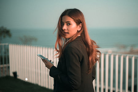 woman standing near white fence and body of water thumbnail