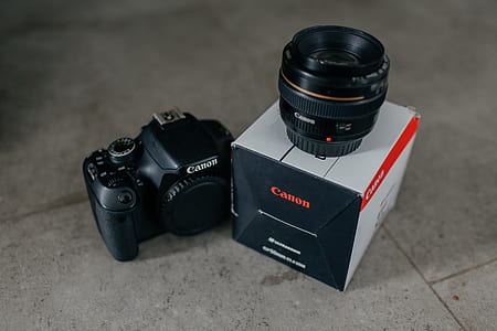 black Canon DSLR camera with lens and box on gray floor tiles thumbnail