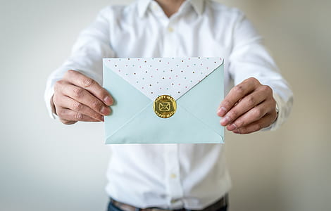 person holding teal and white envelop thumbnail