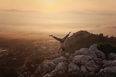 person doing cartwheel on top of rock formation during daytime thumbnail