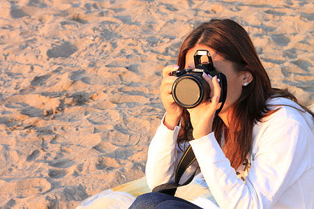 woman using a DSLR camera while sitting on the sand dunes thumbnail