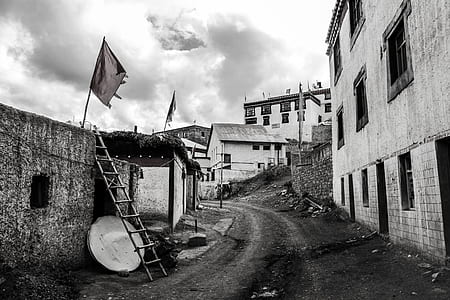 Greyscale Photo Dirt Road Between Buildings thumbnail