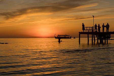 silhouette photography of five person standing on boardwalk during golden hour thumbnail