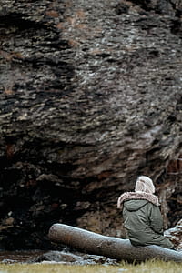 person sitting on log in front of rock formation thumbnail
