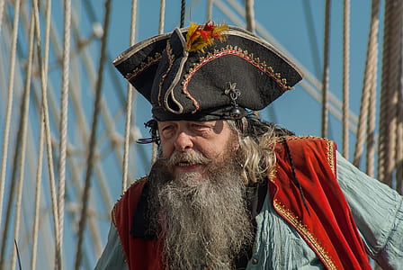 man wearing black pirate hat, red vest, and blue shirt on front of ropes thumbnail
