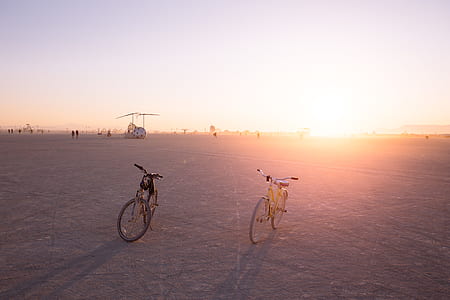 two black and yellow bikes park in road thumbnail