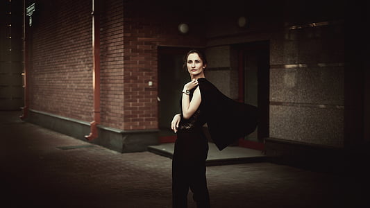 woman wears black sleeveless dress with black scarf near brick building thumbnail