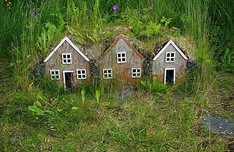 three brown-and-black wooden house miniatures surrounded by plants thumbnail