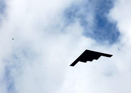 low angle photography of black stealth bomber flying under white skies thumbnail