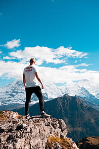 man in white shirt standing on cliff during daytime thumbnail