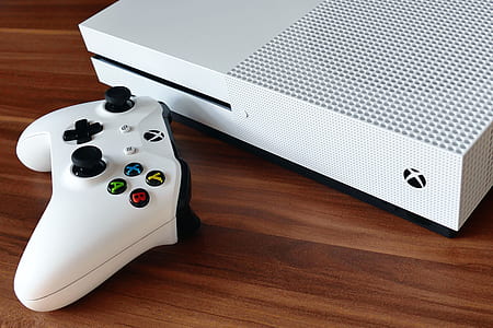 black Xbox One console and controller on brown surface thumbnail