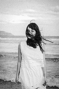 grayscale photography of woman standing on seashore thumbnail