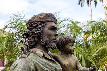 man carrying boy statue near coconut trees during daytime thumbnail