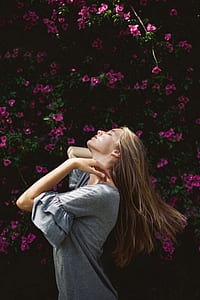 woman closing eyes with head up high standing near pink petaled flowers thumbnail