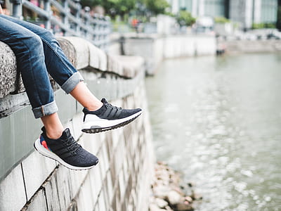 person wearing black sneakers sits on concrete pavement thumbnail