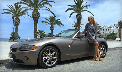 woman in gray long-sleeved dress beside gray BMW convertible coupe during daytime thumbnail