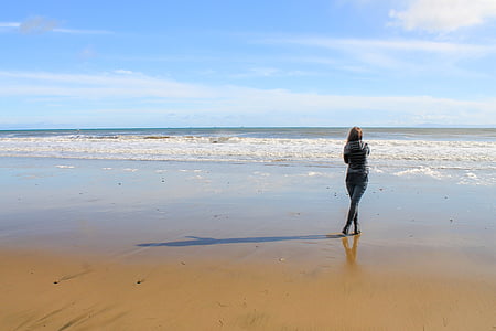 woman standing on shoreline facing back thumbnail