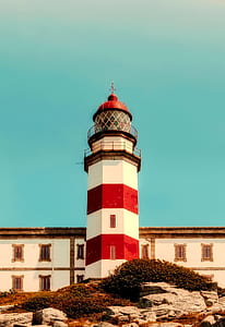 white and red lighthouse under blue sky at daytime thumbnail