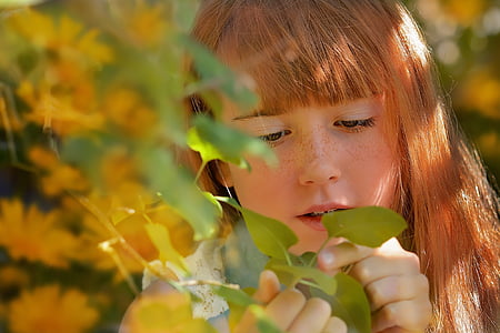 closeup photo of woman with blonde hair holding leaves thumbnail
