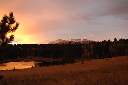 Silhouette Photo of Grass Field With Body of Water and Mountains thumbnail